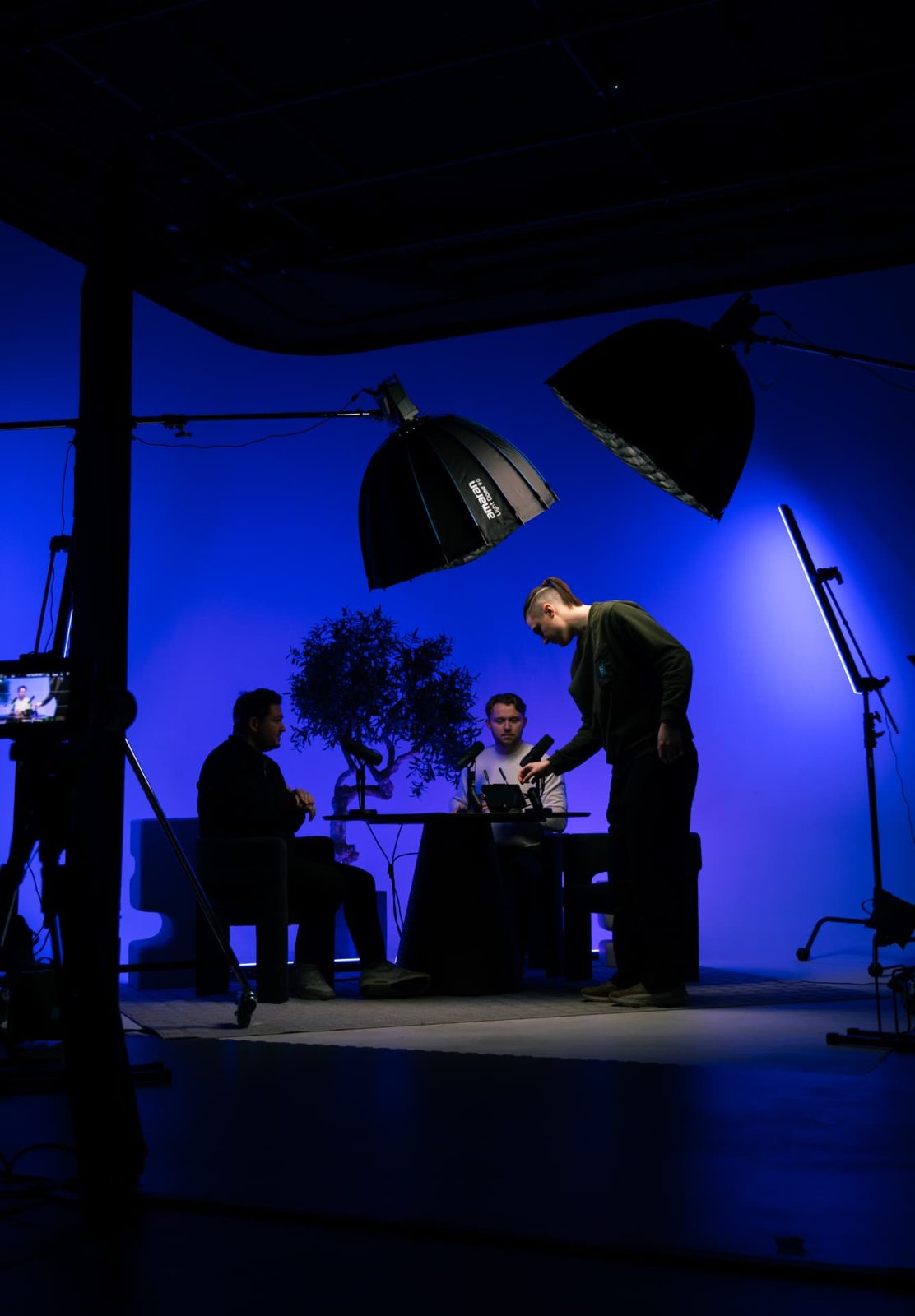 Crew adjusting microphones on a blue-lit studio set mid-record