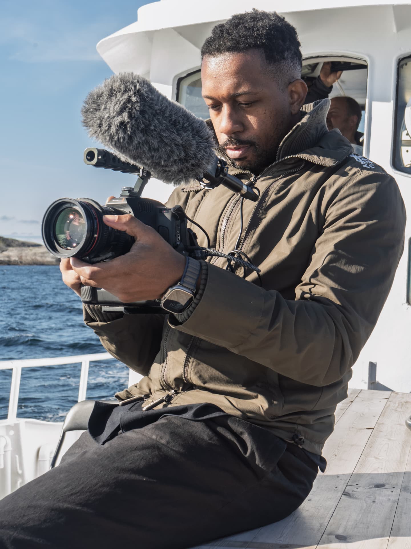 Camera operator checking framing on a rigged cinema camera aboard a boat off the Norwegian coast