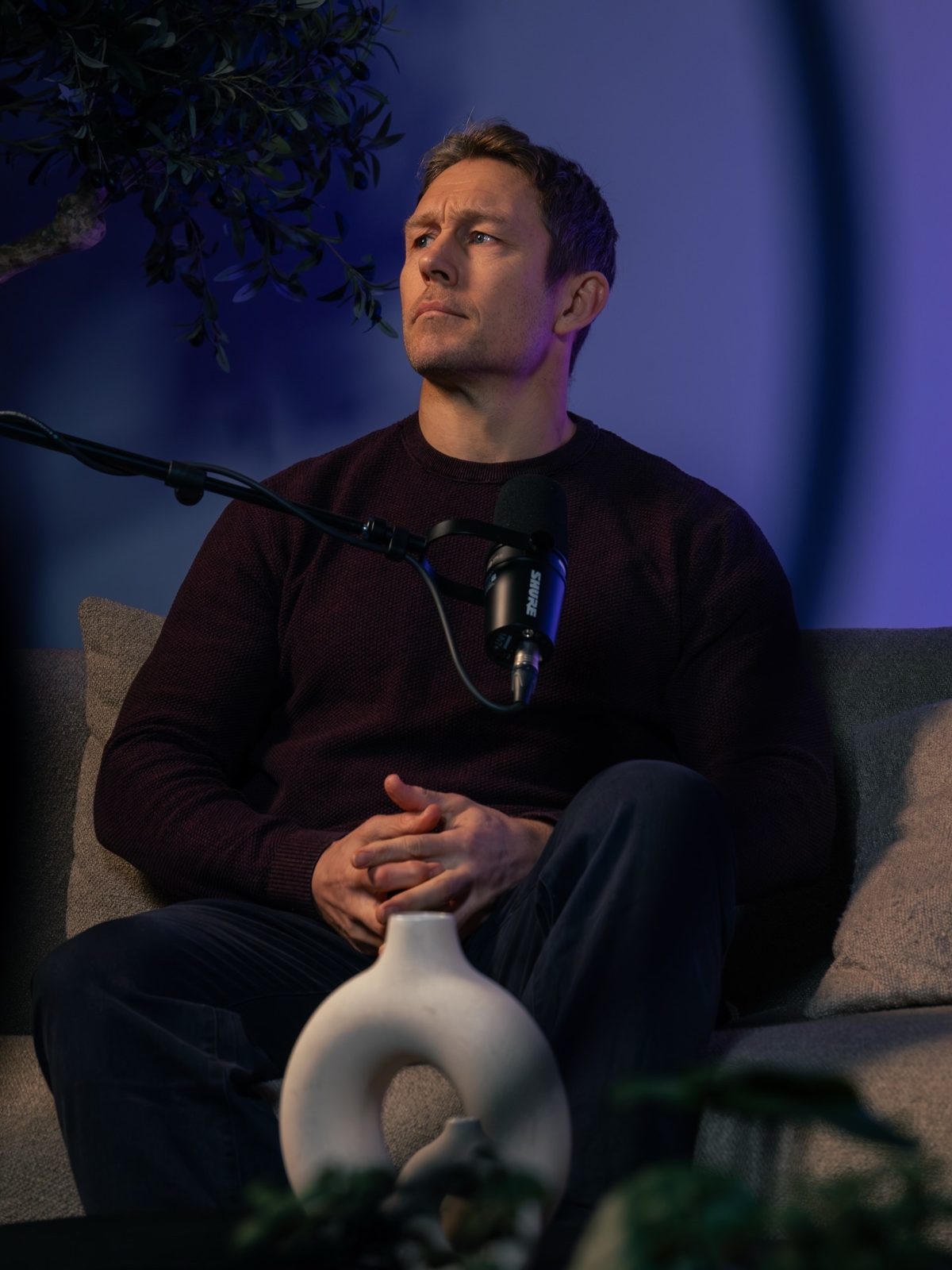 Guest sitting on set under blue light during an interview